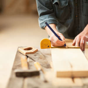 Mature caprenter measuring a wooden plank