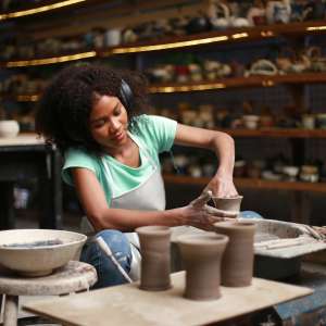 Beautiful woman making ceramic pottery on wheel, hands close-up. woman in freelance, business, hobby.